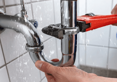 Plumber clearing blocked drain under sink to restore fast, proper drainage