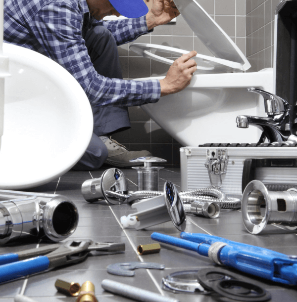 Emergency plumber fixing toilet leak with tools on bathroom floor