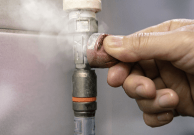 Plumber checking gas leak at valve connection to protect home with safe repairs
