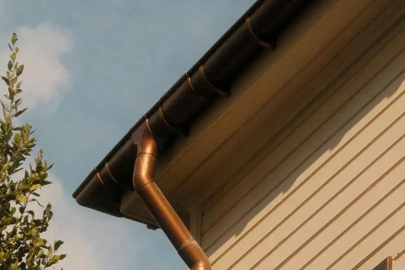 Copper gutter and downpipe installed along residential roof edge