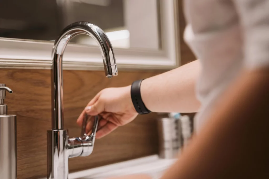 A woman turning off the chrome tap at the bathroom sink